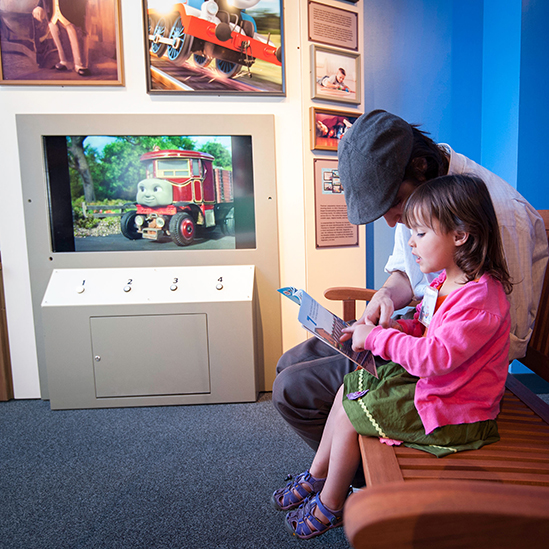 girl and father reading a book on a bench